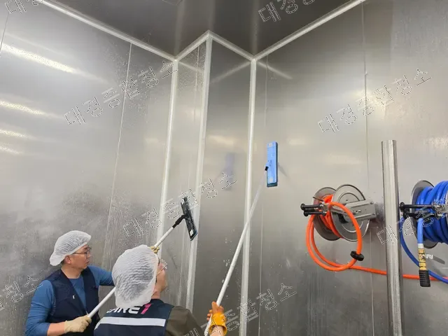 작업자 두 명이 스퀴지로 벽면을 청소하는 모습