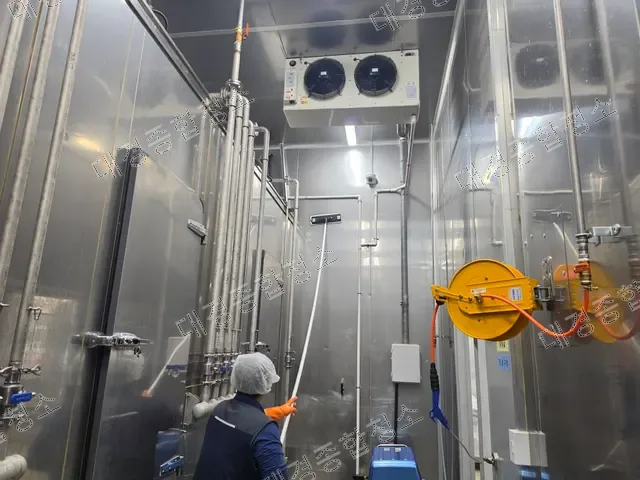 냉각기 아래에서 고압 호스로 세척하는 작업자
