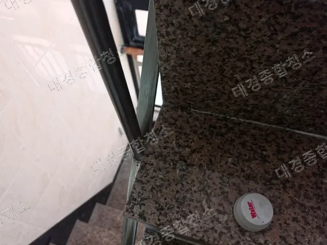 계단에 놓인 원형 누수감지기와 스테인리스 난간