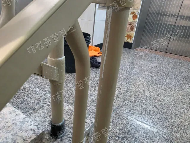 난간 기둥에 흘러내린 흰 석회 자국과 바닥 위 장갑