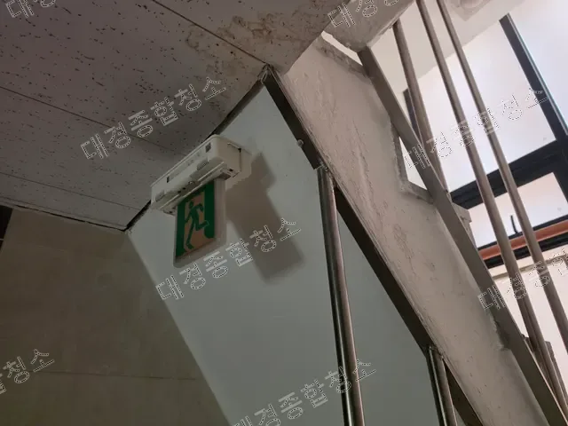 물 얼룩이 번진 천장과 계단실 비상구 유도등