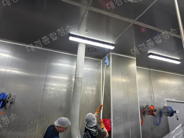 긴 밀대로 스테인리스 벽면을 세척하는 작업자