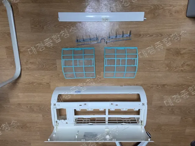바닥에 펼쳐 놓은 분해된 벽걸이 에어컨 부품 전체